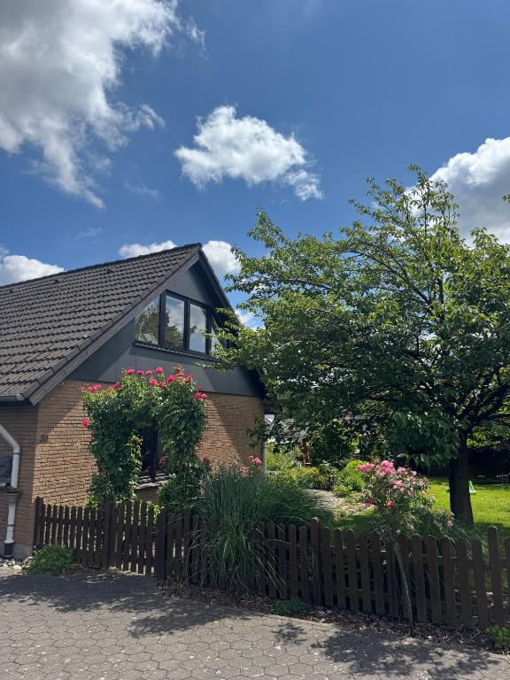 a house with a wooden fence and flowers at 2-Zimmer Ferienwohnung am Teutoburger Wald in Lage