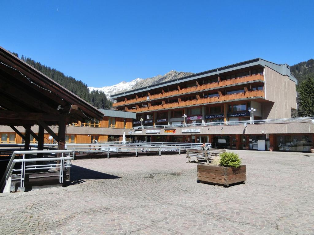 a large building with a courtyard with benches in front of it at Bilocali Alberti - Rainalter in Madonna di Campiglio