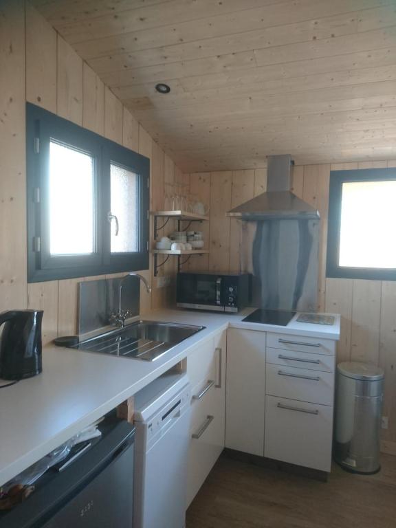 - une cuisine avec des placards blancs, un évier et 2 fenêtres dans l'établissement La Crapouillette, à Lège-Cap-Ferret