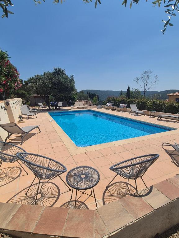 a swimming pool with chairs and a table next to it at Gites Colline De Sollies in Salernes