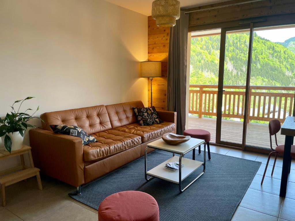 un salon avec un canapé en cuir marron et une table dans l'établissement Appartement charmant au pied des pistes, à Saint-Jean-dʼAulps