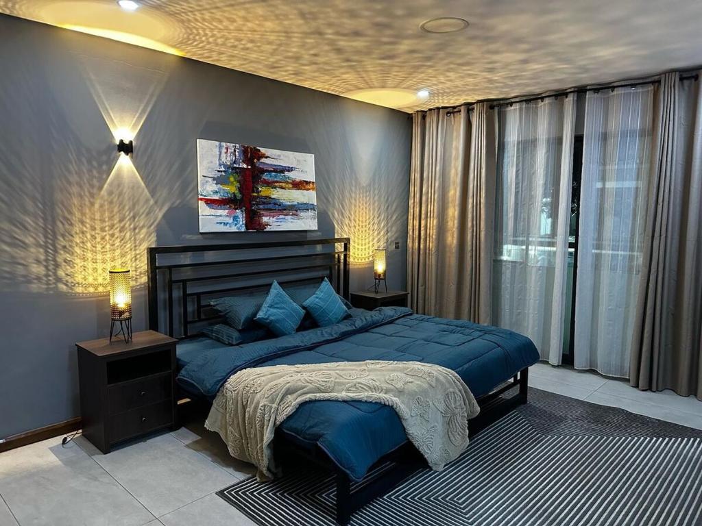 a bedroom with a blue bed and a window at PLSA Lovely Three Bedroom Home in Accra