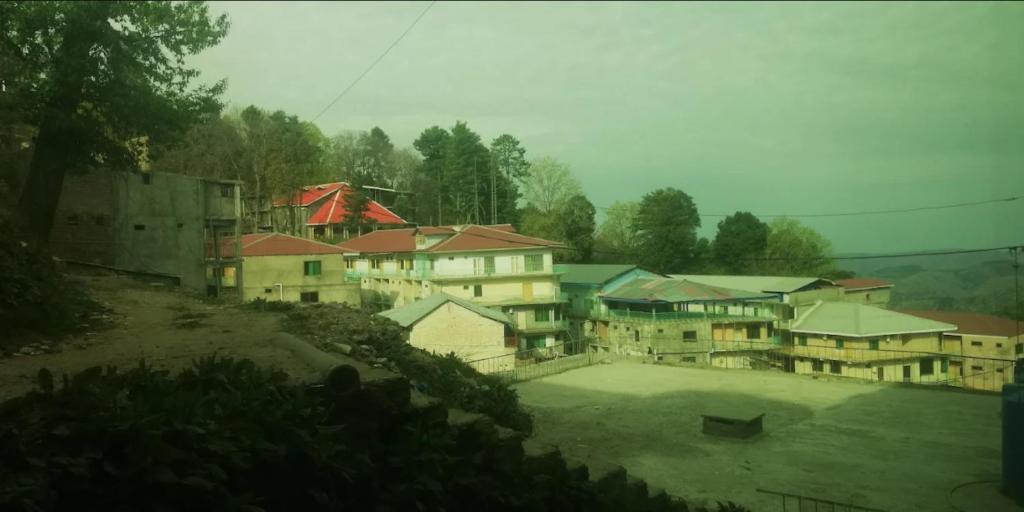 Un grupo de edificios con una cancha de tenis al frente. en Pleasant View Murree, en Murree