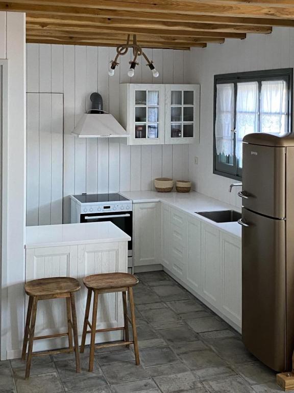 a kitchen with white cabinets and a sink and a refrigerator at Ληγάτο Cottage House in Áyios Pétros