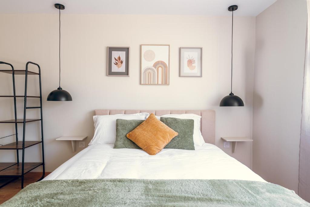 une chambre avec un lit avec des draps blancs et des oreillers verts dans l'établissement L'essentiel, calme et climatisé - Accès autonome, à La Ferté-Gaucher