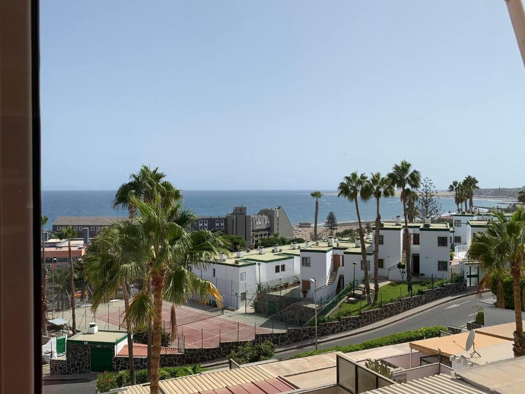 Blick auf eine Stadt mit Palmen und das Meer in der Unterkunft Großzügige Ferienwohnung mit Atlantikblick in zentraler Lage Monte Rojo San Agustín in San Bartolomé de Tirajana