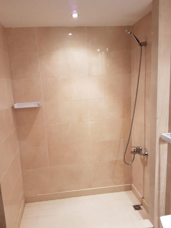 a bathroom with a shower with a tile wall at Grand appartement avec piscines in Cabo Negro