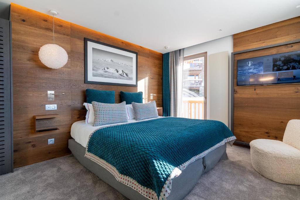 a bedroom with a large bed and a tv at Hotel Pashmina Le Refuge in Val Thorens