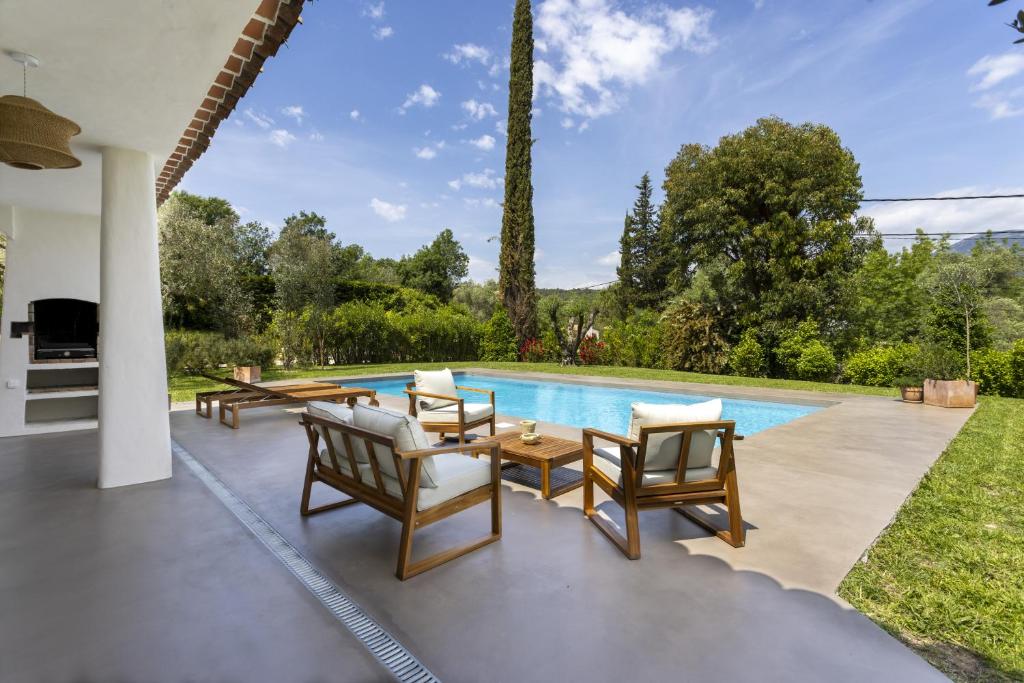 un patio avec une table et des chaises à côté d'une piscine dans l'établissement La Maison Méditerranéenne, à Roquefort-les-Pins