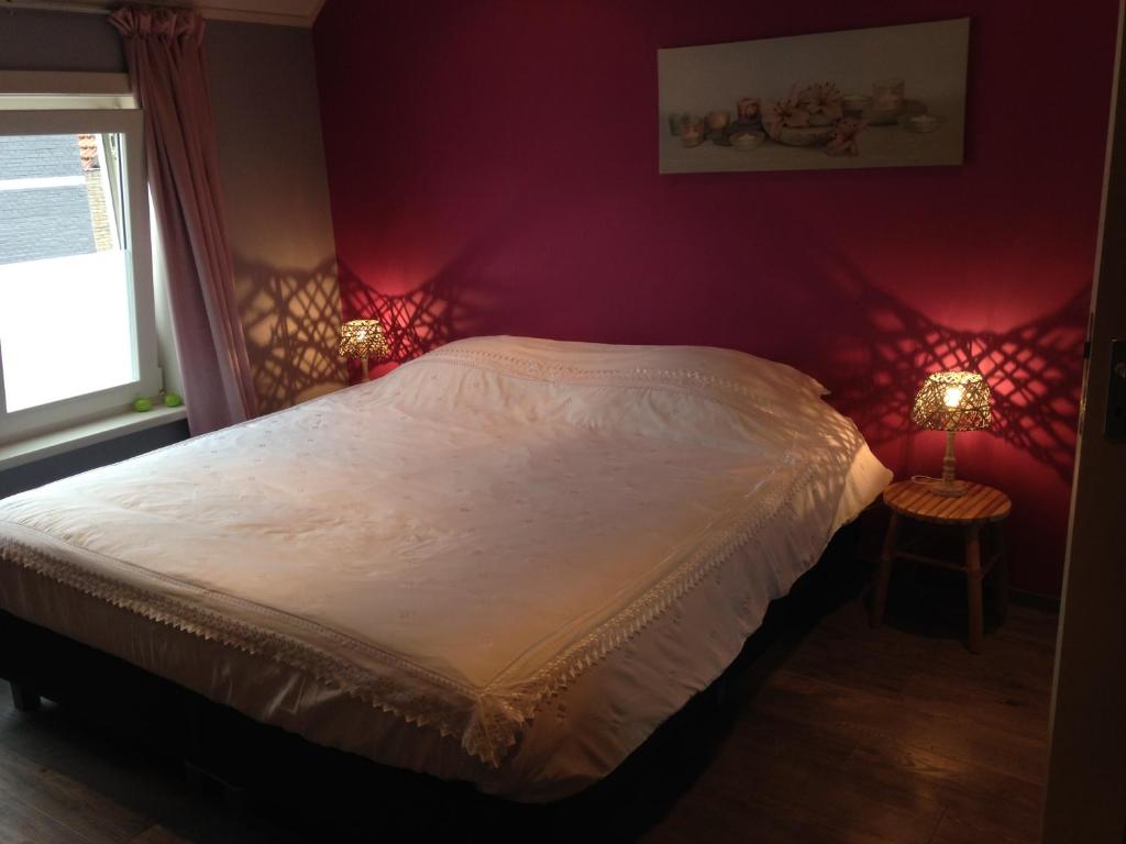 1 dormitorio con 1 cama blanca con luces rojas en Vrije Vlinders, en IJzendijke