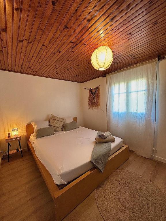 une chambre avec un grand lit avec un plafond en bois dans l'établissement Studio Bougainvillier, à La Seyne-sur-Mer