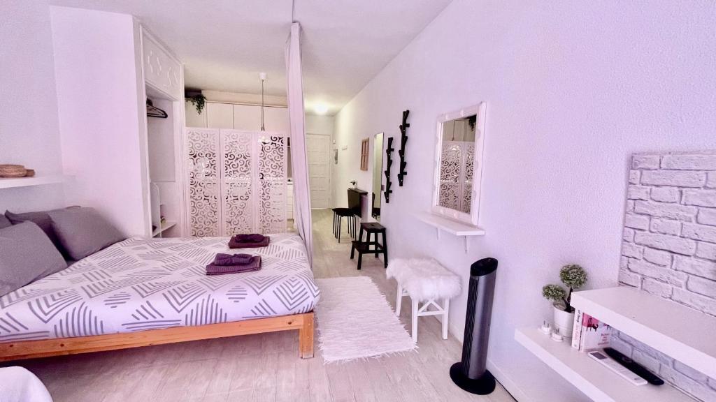 een witte kamer met een bed en stoelen erin bij Los cristianos Vistas al mar y cerca de la playa in Los Cristianos