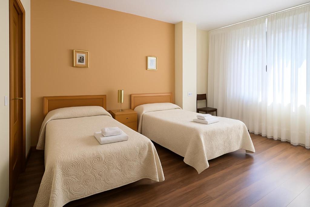 una habitación con dos camas con sábanas blancas en Pension Gelin, en Carrizo de la Ribera