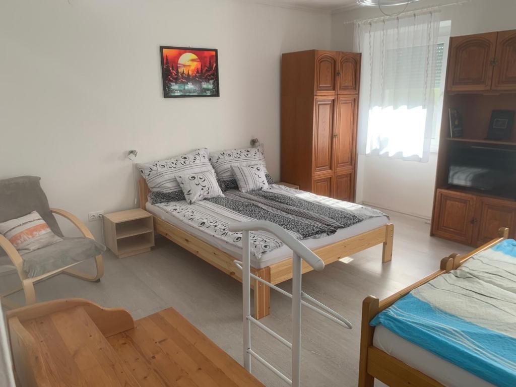 a bedroom with a bed and a chair in it at Fészek Apartmanház in Tapolca