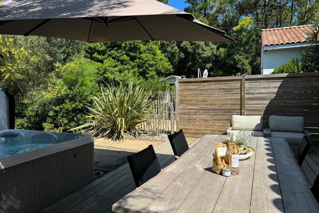 a wooden table with an umbrella next to a hot tub at Villa Brésil - Domaine Le Sherwood in Notre-Dame-de-Monts