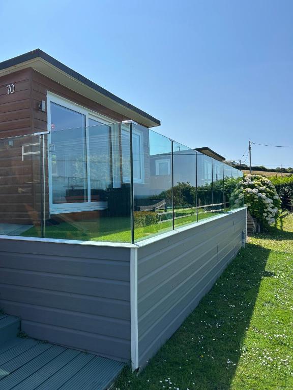 a house with glass windows on a deck at Bovisand Beach Area Chalet, 2-Bed Sea View with Gated Parking & BBQ in Plymouth
