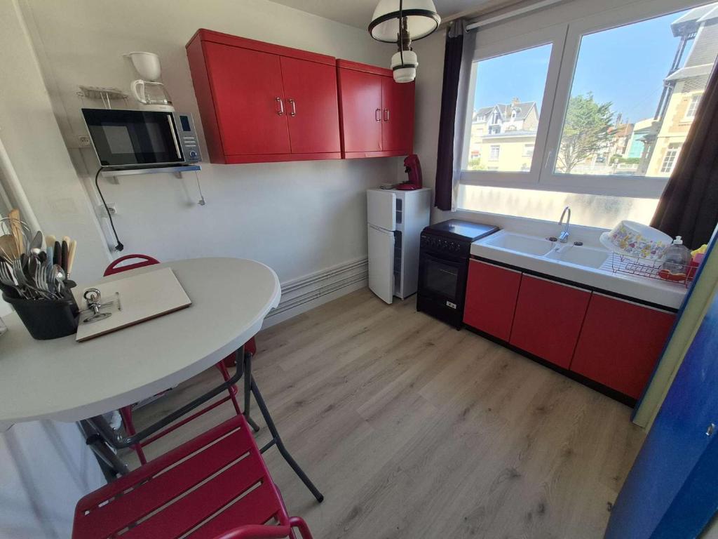 Elle comprend une petite cuisine avec des placards rouges et un réfrigérateur blanc. dans l'établissement Charmant T2 de 20m² face à la plage de Berck-sur-Mer, avec chambre et ascenseur - FR-1-674-48, à Berck-sur-Mer