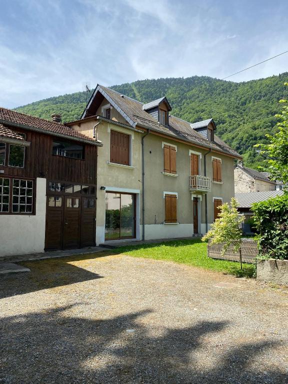une grande maison avec une allée en face d'une montagne dans l'établissement Belle maison de ville au centre de Luchon, à 200m des Télécabines !, à Luchon
