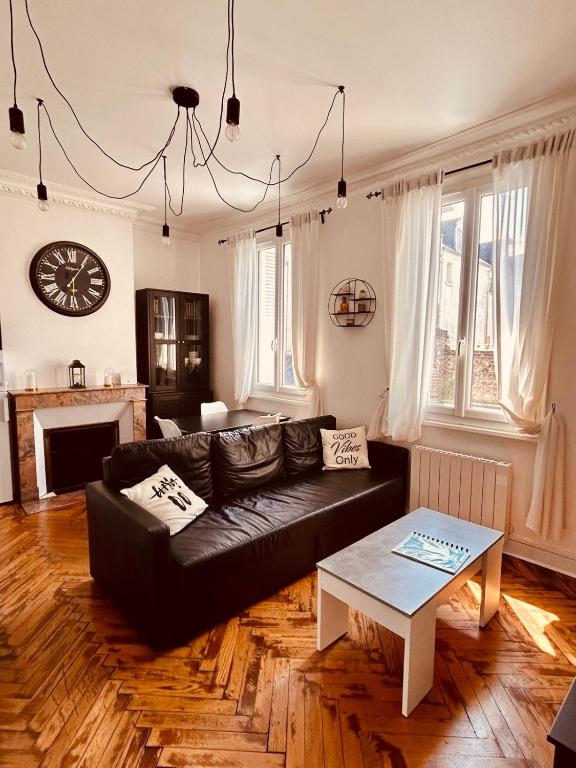 un salon avec un canapé noir et une table dans l'établissement L'Atelier Normand, à Fécamp