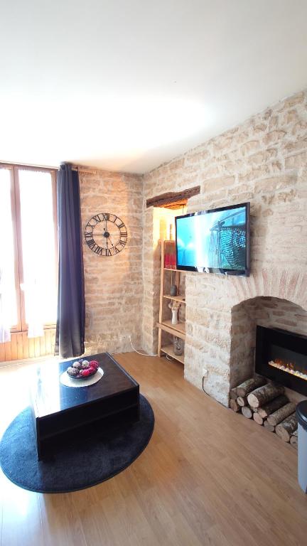 - un salon avec un mur en pierre et une cheminée dans l'établissement Le Clos des Perrières, à Dijon