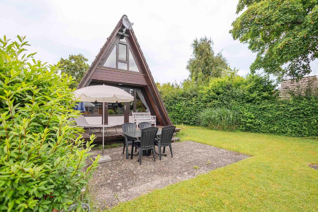 un kiosque avec des chaises et un parasol dans une cour dans l'établissement Ferienwohnpark Immenstaad am Bodensee Nurdachhaus Typ 7 ND 50, à Immenstaad am Bodensee