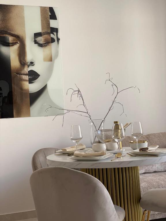 a table with wine glasses and a picture of a woman at Apartament Echo Park in Olecko