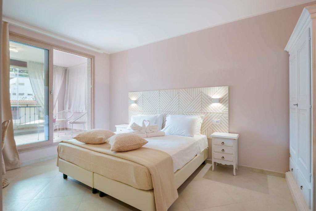 a white bedroom with a bed and a window at La Rosa dei Venti Guesthouse in Villasimius