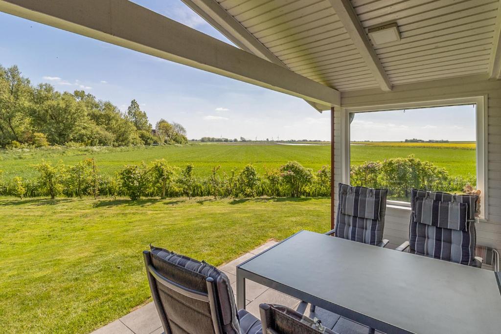 a table and chairs on a porch with a view of a field at Schimmelreiter in Simonsberg