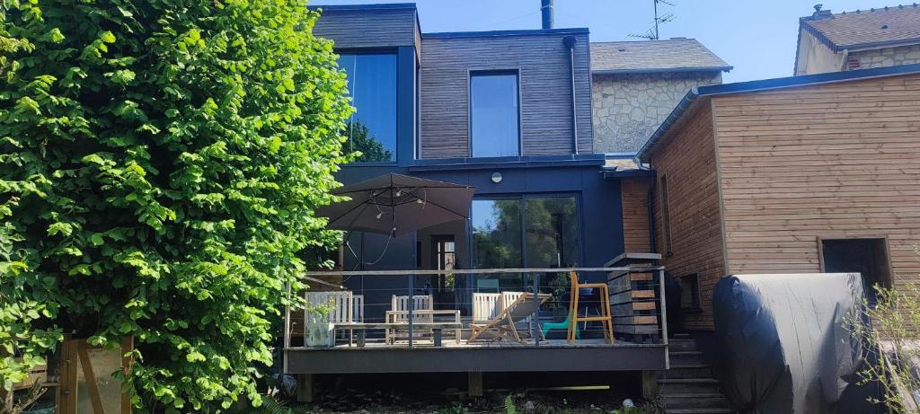 une maison avec une terrasse dotée de chaises et d'un parasol dans l'établissement Caen, très jolie maison à deux pas du mémorial, à Caen