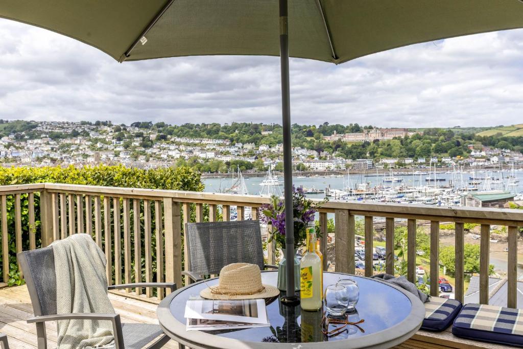 a table with a hat on a balcony with a view of a harbor at River Retreat in Kingswear