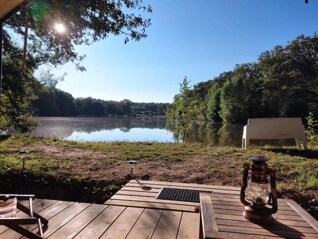 a view of a lake with a lantern on a wooden deck at Domaine de l'Atrée - Tente Maasaï Poyaudine in Saint-Martin-des-Champs