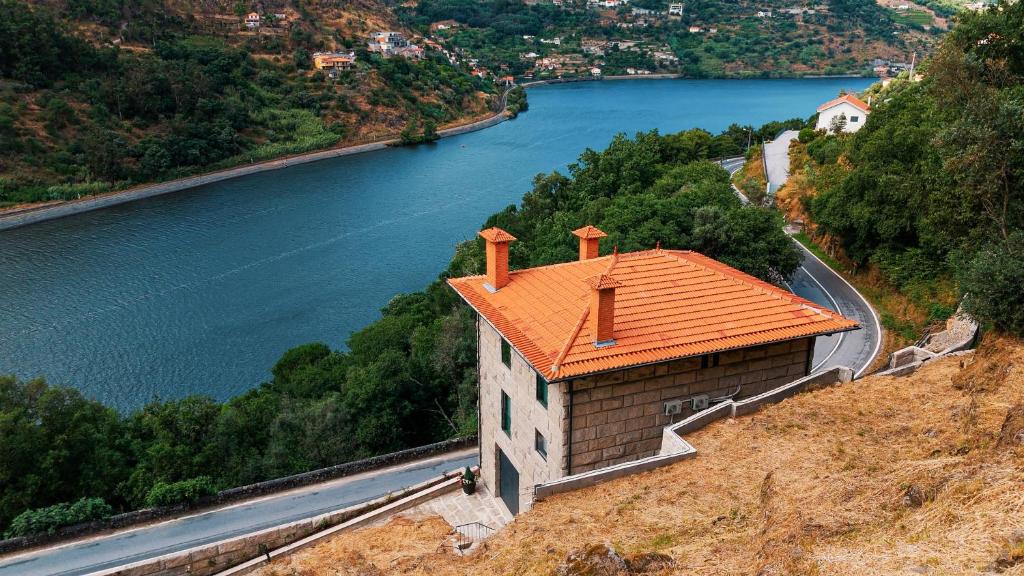 un edificio con un tetto arancione su una collina accanto a un fiume di Douro Sky Valley - Private Villa a Miomães
