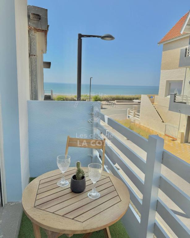 une table et une chaise sur un balcon avec vue sur l'océan dans l'établissement Maison Sable & Mer, à Merlimont