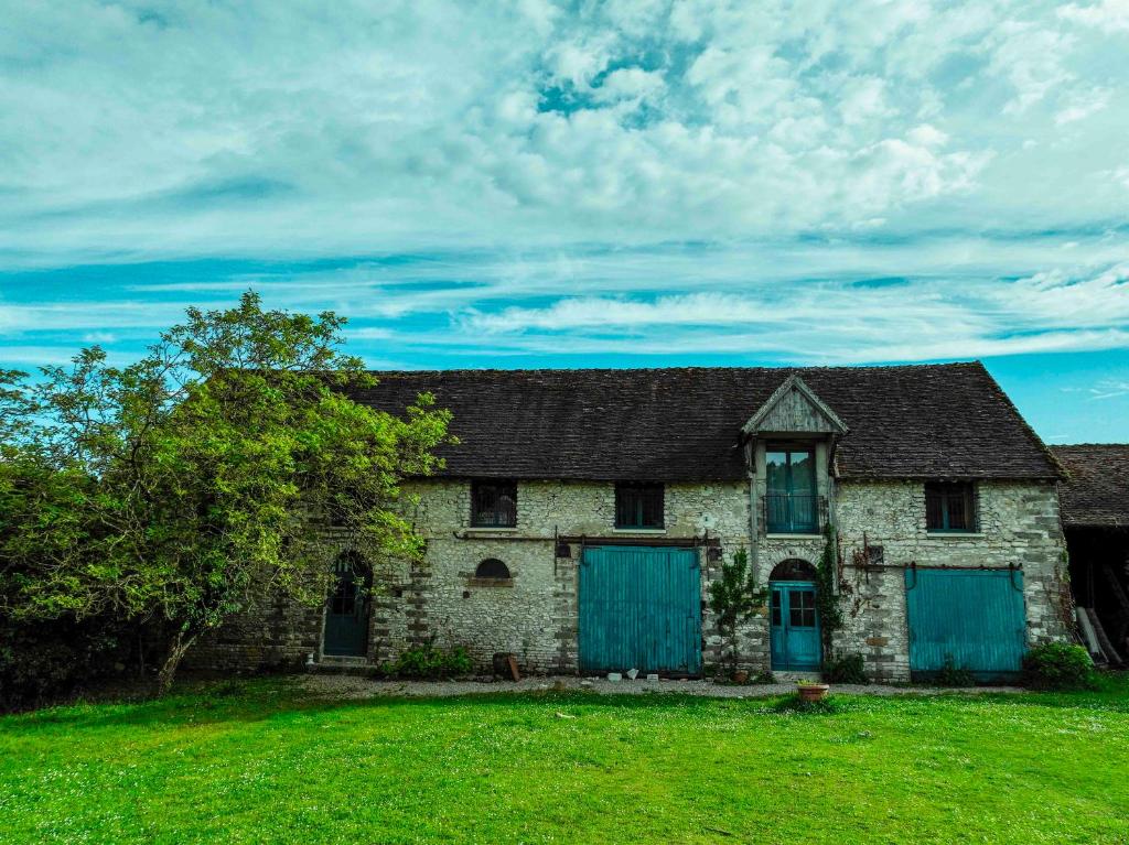 une ancienne maison en pierre avec des portes bleues sur un champ dans l'établissement Ferme de la Haute Maison Maison d hotes, à Saint-Loup-de-Naud