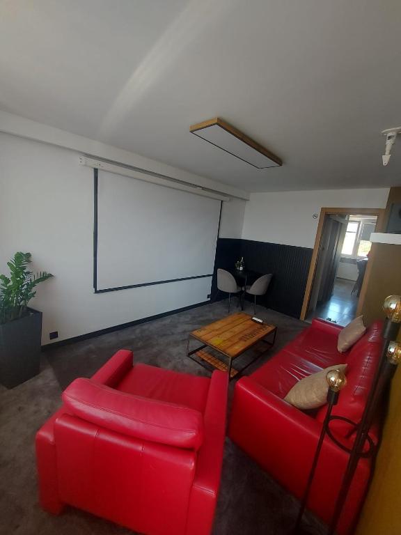 a living room with a red couch and a screen at Apartament Dziesiątka in Bolesławiec