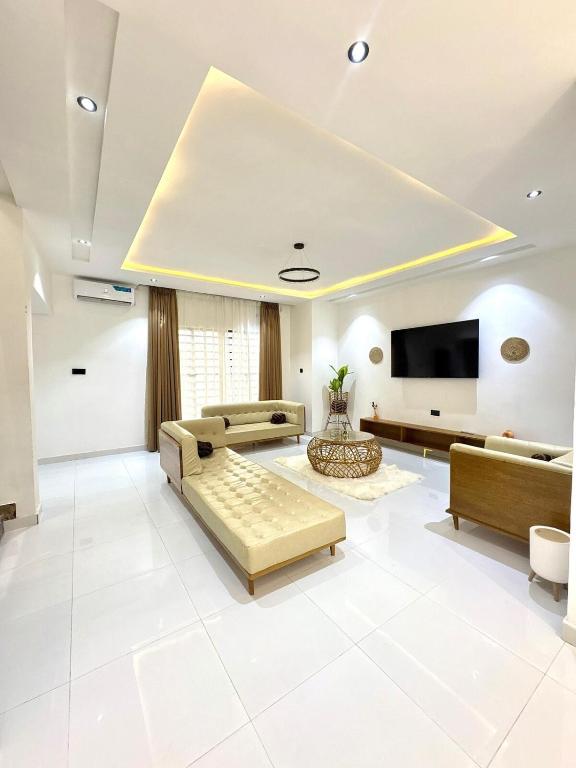 een grote woonkamer met banken en een flatscreen-tv bij Oaksvale Homes in Enugu