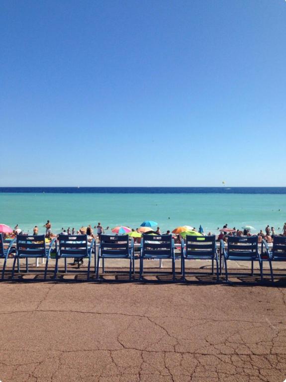 un groupe de personnes assises sur une plage avec des parasols dans l'établissement Superbe appartement de 3p pieces dans residence avec piscine et climatisation, à Nice