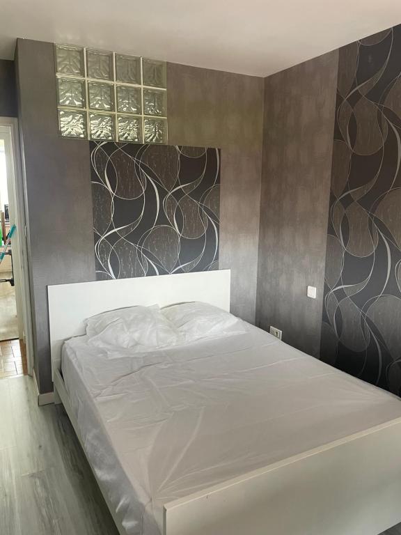 - une chambre avec un lit blanc et un mur dans l'établissement Appartement tout confort, à Tarbes