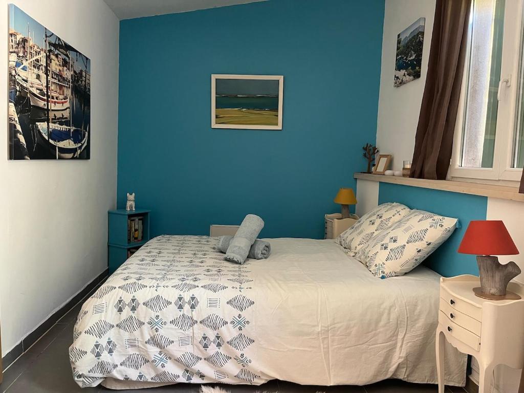 - une chambre bleue avec un lit et un mur bleu dans l'établissement T2 en entrée de Cassis, à Cassis