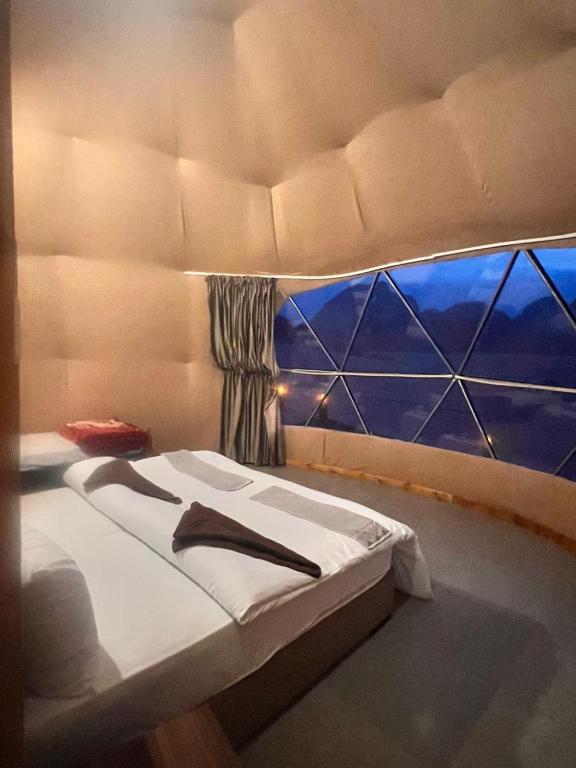a bed in a room with a window at Layla Wadi Rum in Disah