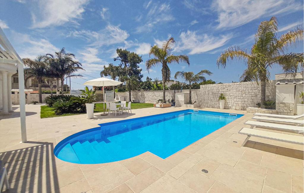 a blue swimming pool in a yard with palm trees at 1 Bedroom Awesome Home In Leporano in Leporano