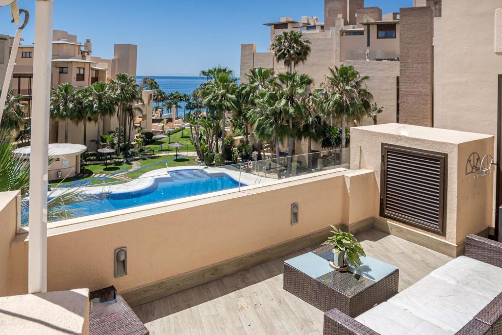 an apartment balcony with a swimming pool and palm trees at BP7C.2A Beachfront Penthouse with Private Pool in Estepona