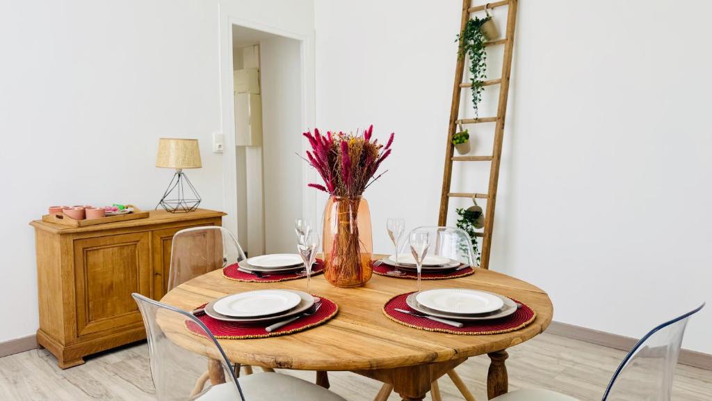 - une table à manger avec des chaises et un vase fleuri dans l'établissement L'Instant Bohème - Parking - Proche gare & Wifi, à Sainte-Savine