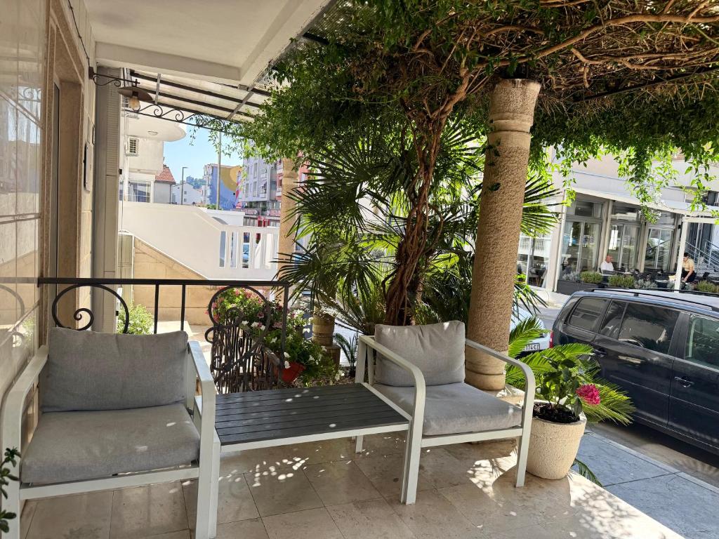 two chairs sitting on a porch with a palm tree at Hotel Villa Perla Di Mare in Budva