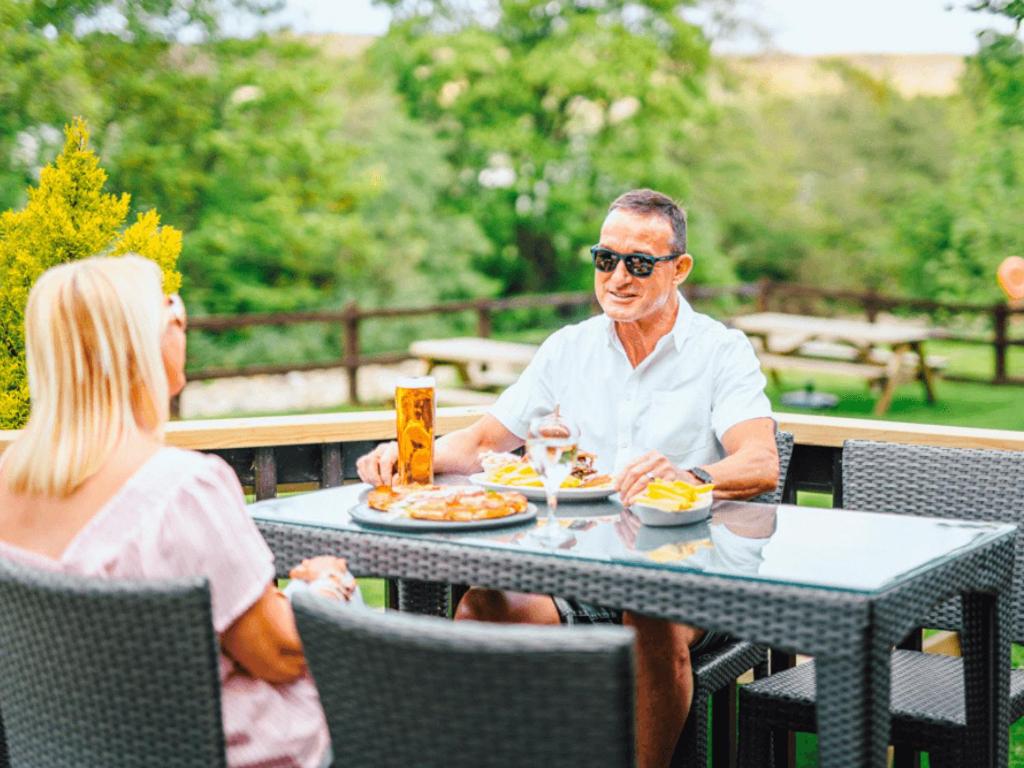 a man and woman sitting at a table eating food at Heather View Leisure Park - Ivy Caravan 6 in Stanhope