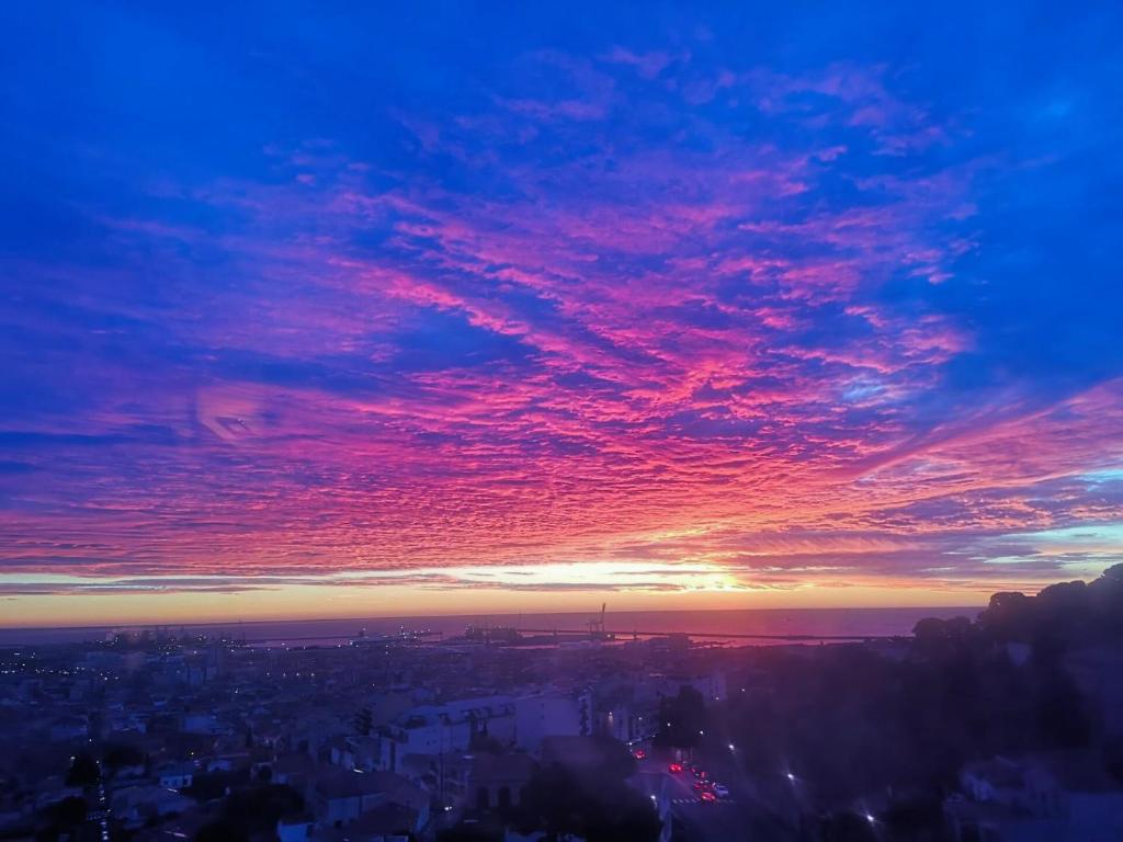 une vue du coucher de soleil sur une ville avec un rose dans l'établissement Le Grand Bleu, à Sète