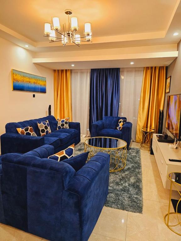 a living room with blue couches and a tv at Ella Homes in Nairobi