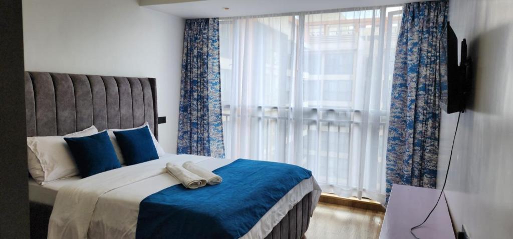 a bedroom with a large bed with blue curtains at Ella Homes in Nairobi