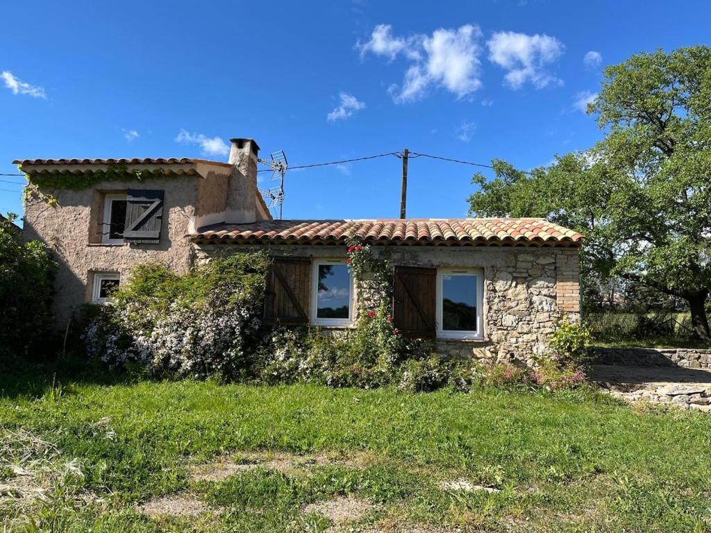 une petite maison en pierre dans un champ herbeux dans l'établissement Maison de charme avec piscine, à Trans-en-Provence