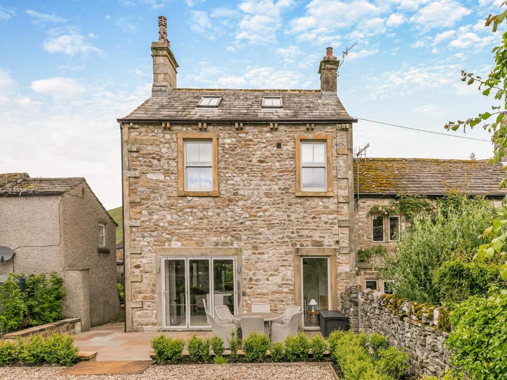 an old stone house with patio furniture in front of it at Prospect House in Kettlewell